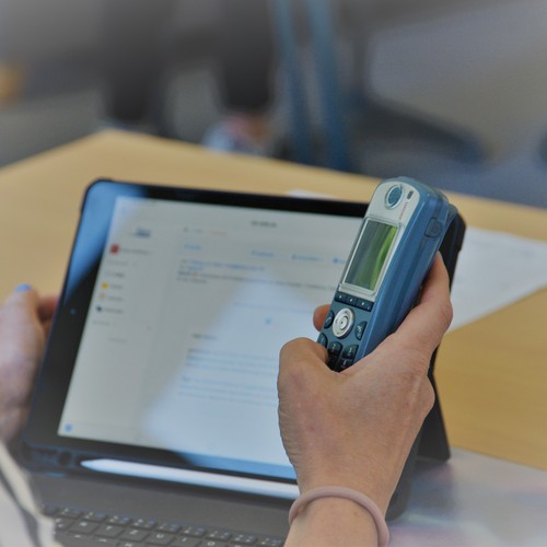 eine Person hält in einer Hand ein iPad und in der anderen ein Telefon