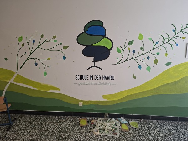 Logo der Schule wird an die Wand gemalt.